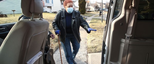Woman entering car with mask and cane